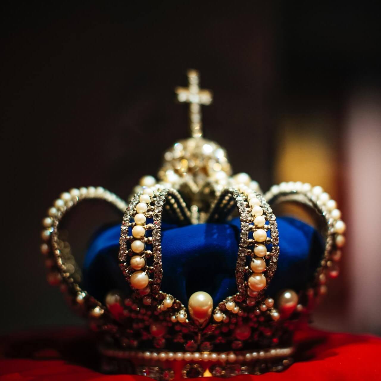 Picture of Crown with blue velvet adorned with pearls and a cross on top.